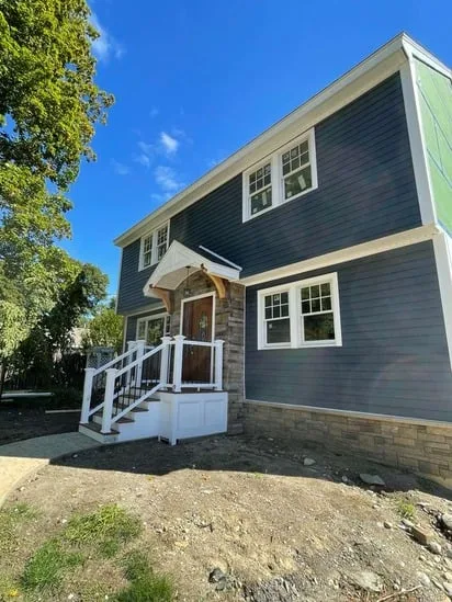 Wide-angle view of the completed exterior renovation featuring LP siding stone Hudson.