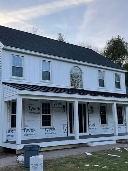 Front porch framing and house wrap under a vinyl siding and porch project.