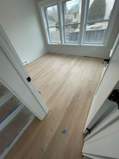 Bright room with multiple windows featuring newly laid boards from a hardwood flooring Shrewsbury MA project.